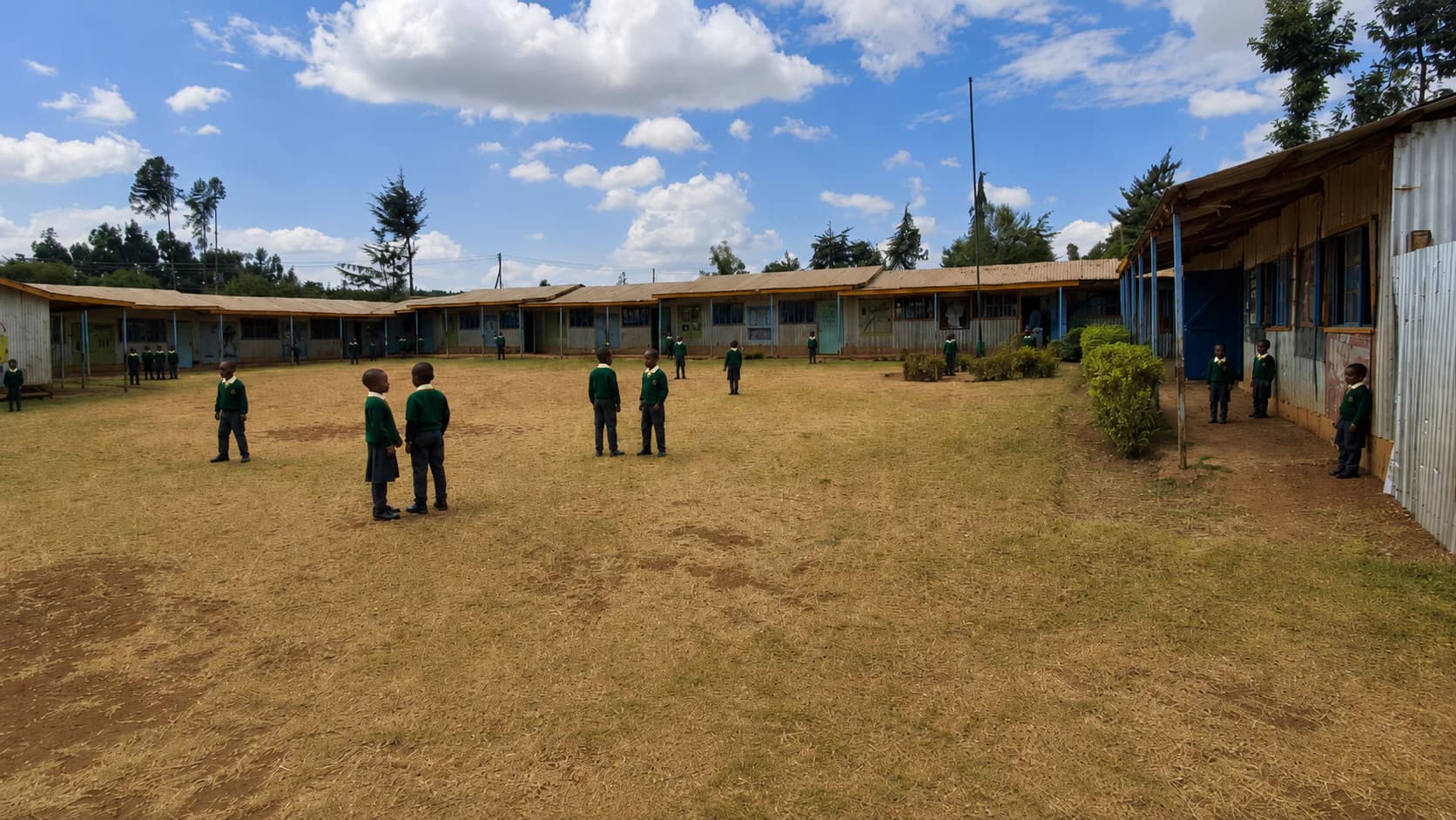 Learners in the Betha Academy courtyard with classroom blocks surrounding the open grounds